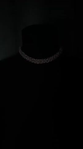 The video displays a close-up shot of a shimmering choker necklace, likely made of rhinestones or crystals, against a dark, opaque background. The necklace is draped around the neck of a black mannequin bust. The background is a deep, dark color, with a subtle, darker green fabric visible behind the bust, suggesting a studio or display setting rather than an outdoor environment. The lighting is dim, highlighting the sparkle of the necklace and creating a dramatic effect. The video is static, with no visible movement or action, focusing solely on the presentation of the jewelry. There is no visible text, nor any cues about the time of day or weather. The overall impression is one of elegance and a focus on the intricate detail of the necklace. The location context of Salekhard, Russia, does not provide any discernible visual cues within the video itself.