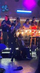 Nightclub patrons dance under colorful lights in Lima