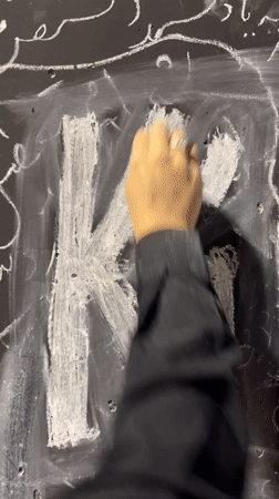 Chalk writing in Farsi and English on a black surface in Tehran