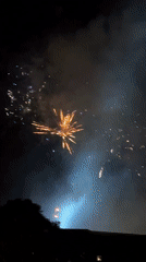 Colorful fireworks display observed from elevated perspective above rooftops