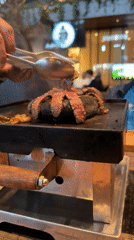 Diner grills steak at table in Mexican restaurant