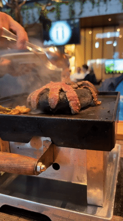 Diner grills steak at table in Mexican restaurant