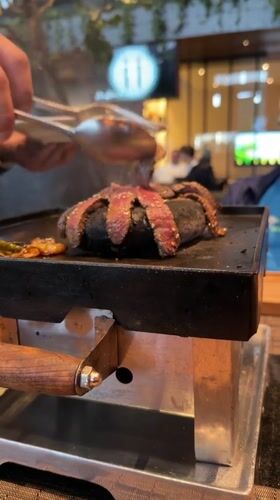Diner grills steak at table in Mexican restaurant