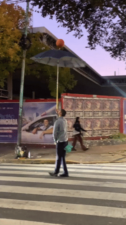 Street performer juggles basketball on umbrella in Buenos Aires