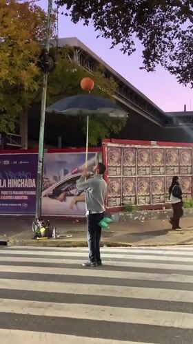 Street performer juggles basketball on umbrella in Buenos Aires
