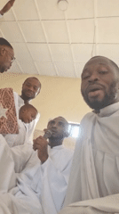 Five people in white robes gather in room