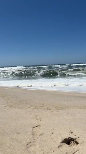 Empty beach in Torreira under clear skies, Atlantic waves rolling in