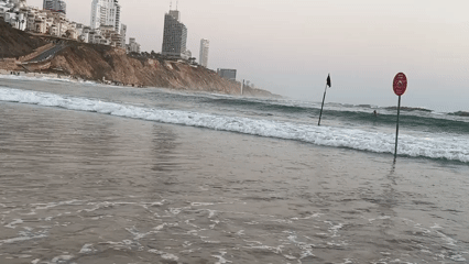 Netanya beachfront with cliff buildings and flagged surf poles