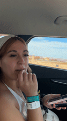 Woman laughing with phone in car passenger seat, La Quinta
