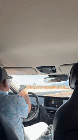 Woman laughing with phone in car passenger seat, La Quinta