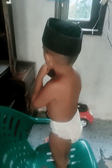 Toddler on a plastic chair, snacking indoors in North Aceh
