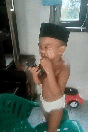 Toddler on a plastic chair, snacking indoors in North Aceh