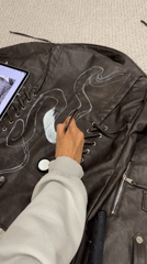 Artist hand-paints white flame design on leather jacket