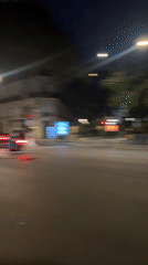 Scooters navigate wet Paris crosswalk at night