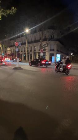 Scooters navigate wet Paris crosswalk at night