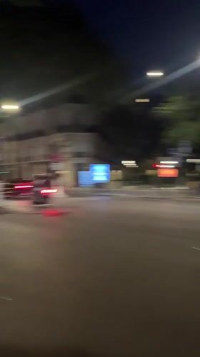 Scooters navigate wet Paris crosswalk at night