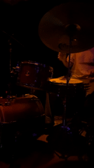 Musicians perform in dimly lit venue under red lights