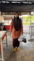 Woman in hijab walks through covered area in Lhokseumawe