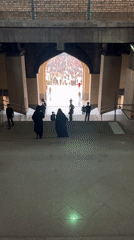 Crowd flows down a grand staircase toward an arched hall in Tehran