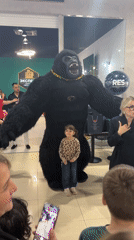 Group poses with costumed gorilla performer in Russian mall
