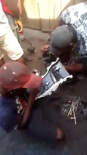 Mechanics repair car engine at outdoor shop in Onitsha