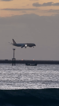 Sunset hour on Kuta Beach, waves, sand, and a plane overhead