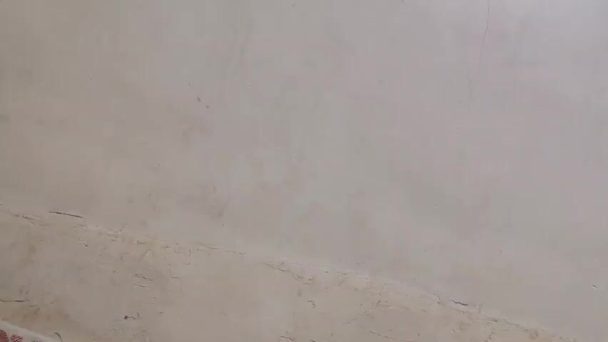 A white painted wall is the sole visible element, with a knocking sound suggesting an interaction possibly occurring off-screen.