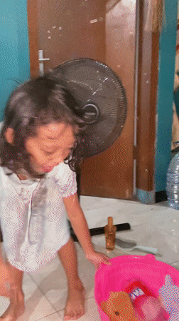 Child fed rice, plays indoors in Gelam, Indonesia
