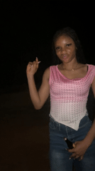 Woman dances with bottle during nighttime gathering in Ogbe