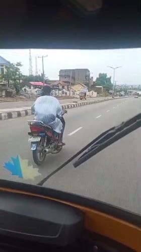 Motorcyclist in striped shirt travels paved road in Lokoja