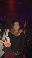 Club dancing under purple and pink lights, cigarette in hand.