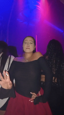 Club dancing under purple and pink lights, cigarette in hand.