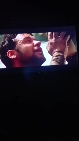 The video shows a close-up of a man's face, likely from a movie or TV show, as he appears to be experiencing a moment of intense emotion. His eyes are closed, and his mouth is slightly open. A hand is visible reaching towards his face, though the person it belongs to is out of frame. The lighting suggests an indoor setting, possibly a dimly lit room or a scene with dramatic lighting. The overall mood is somber and emotional.