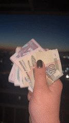 Person counts rubles overlooking Sochi cityscape at dusk