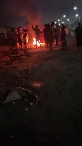 Group gathers around nighttime bonfire in Alaguntan, Nigeria