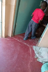 Man trims grass with machete while child watches in Turbo