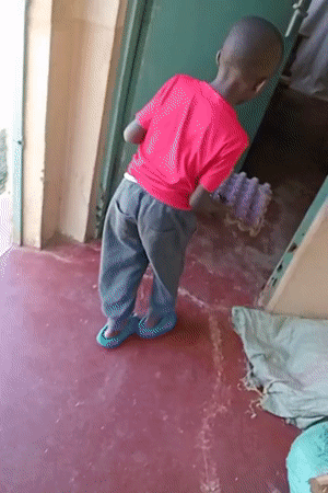 Man trims grass with machete while child watches in Turbo