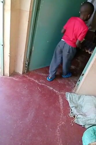 Man trims grass with machete while child watches in Turbo