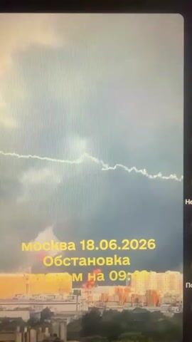 A video displays a cloudy sky with a bright, vertical streak of light, possibly a lightning strike or an explosion, descending from the clouds. Overlay text in yellow reads "москва 18.06.2026" and "Обстановка на 09:40". The bottom of the frame shows a cityscape with buildings.