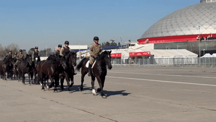 Military equestrian procession near a domed Santiago landmark