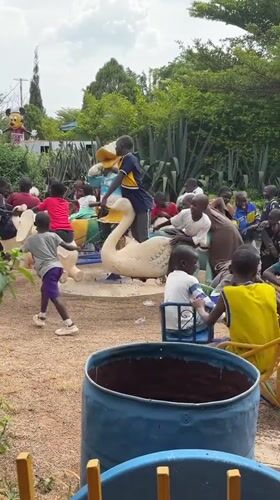 Children play while couple examines car engine in Nigeria