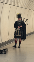 Bagpiper in Scottish dress performs in London Underground station