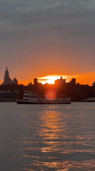 Fiery NYC harbor sunset, skyline silhouetted at golden hour