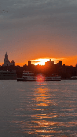 Fiery NYC harbor sunset, skyline silhouetted at golden hour