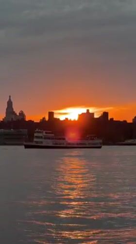 Fiery NYC harbor sunset, skyline silhouetted at golden hour