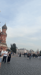 Tourists photograph Red Square landmarks under cloudy Moscow afternoon