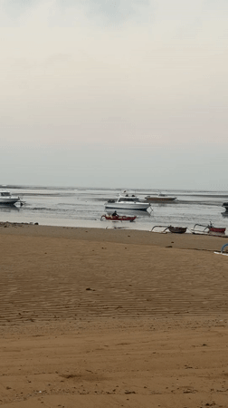 Calm Bali beach at dusk with moored boats and pastel skies