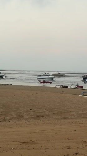 Calm Bali beach at dusk with moored boats and pastel skies