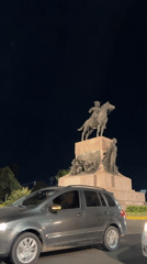 Car idles near equestrian monument in Buenos Aires at night
