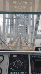 Train cab ride across a metal truss bridge over a river